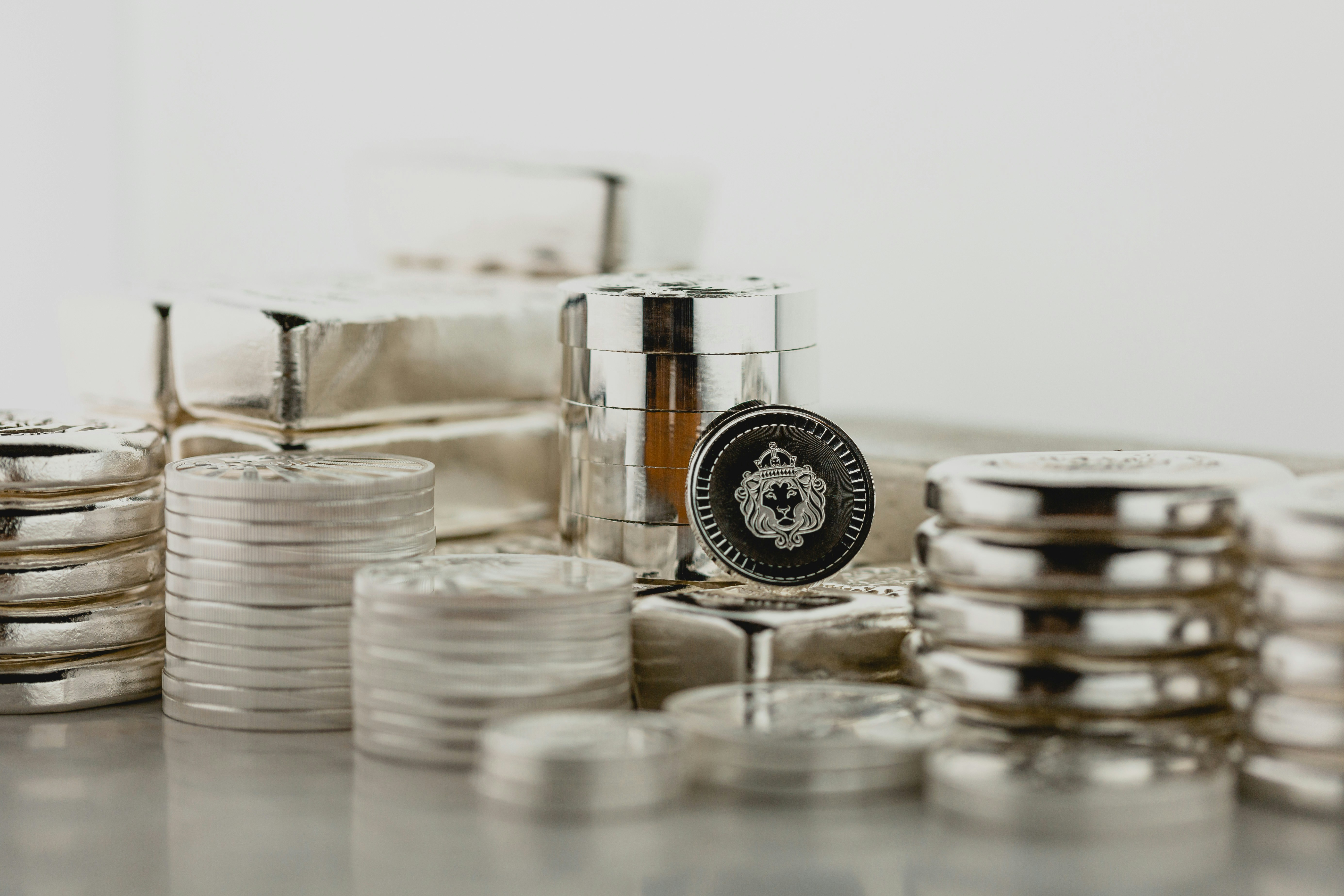 Silver coins and bars arranged with protective storage containers on a light surface.