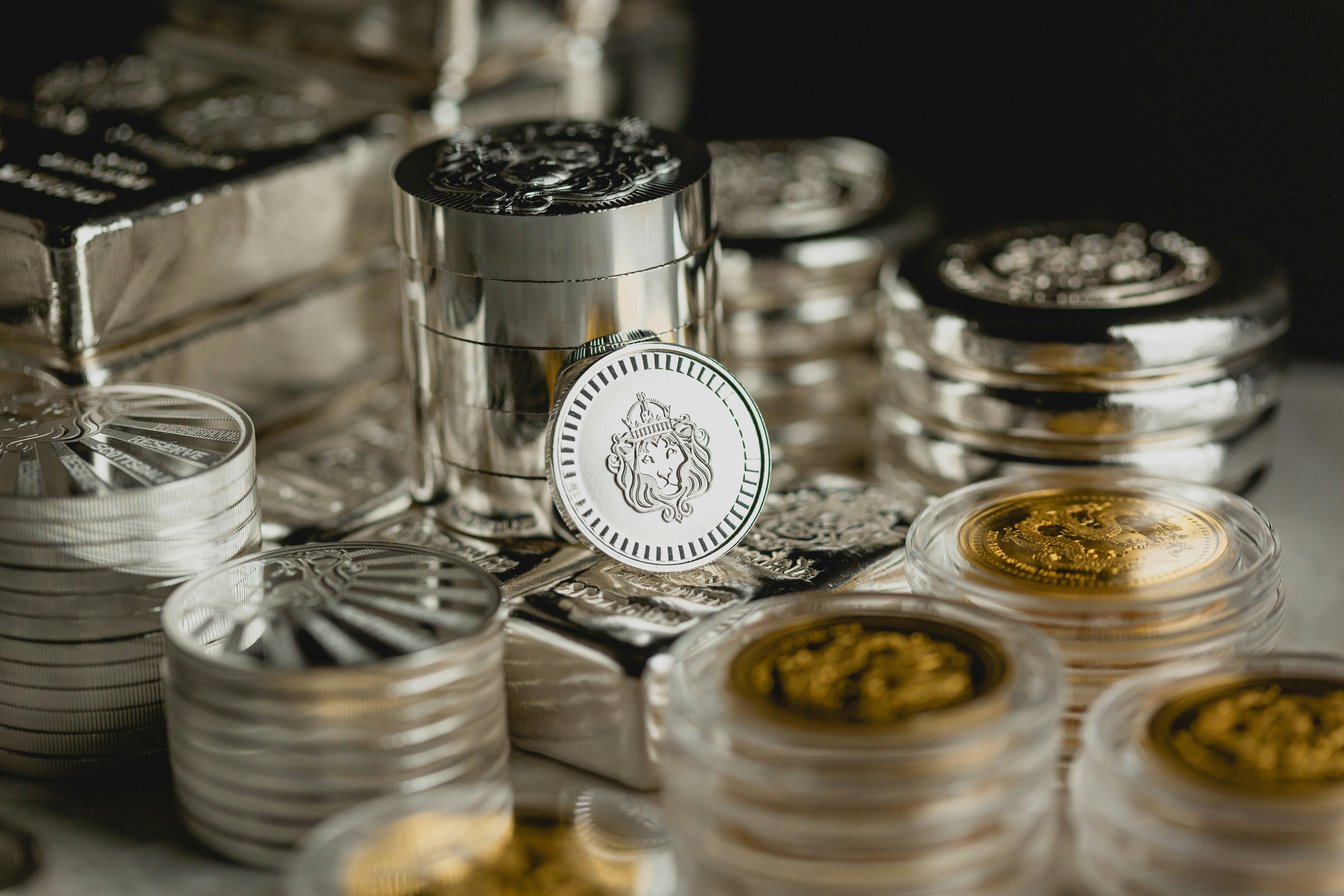 A collection of precious metal coins and bars in protective cases on a neutral background.