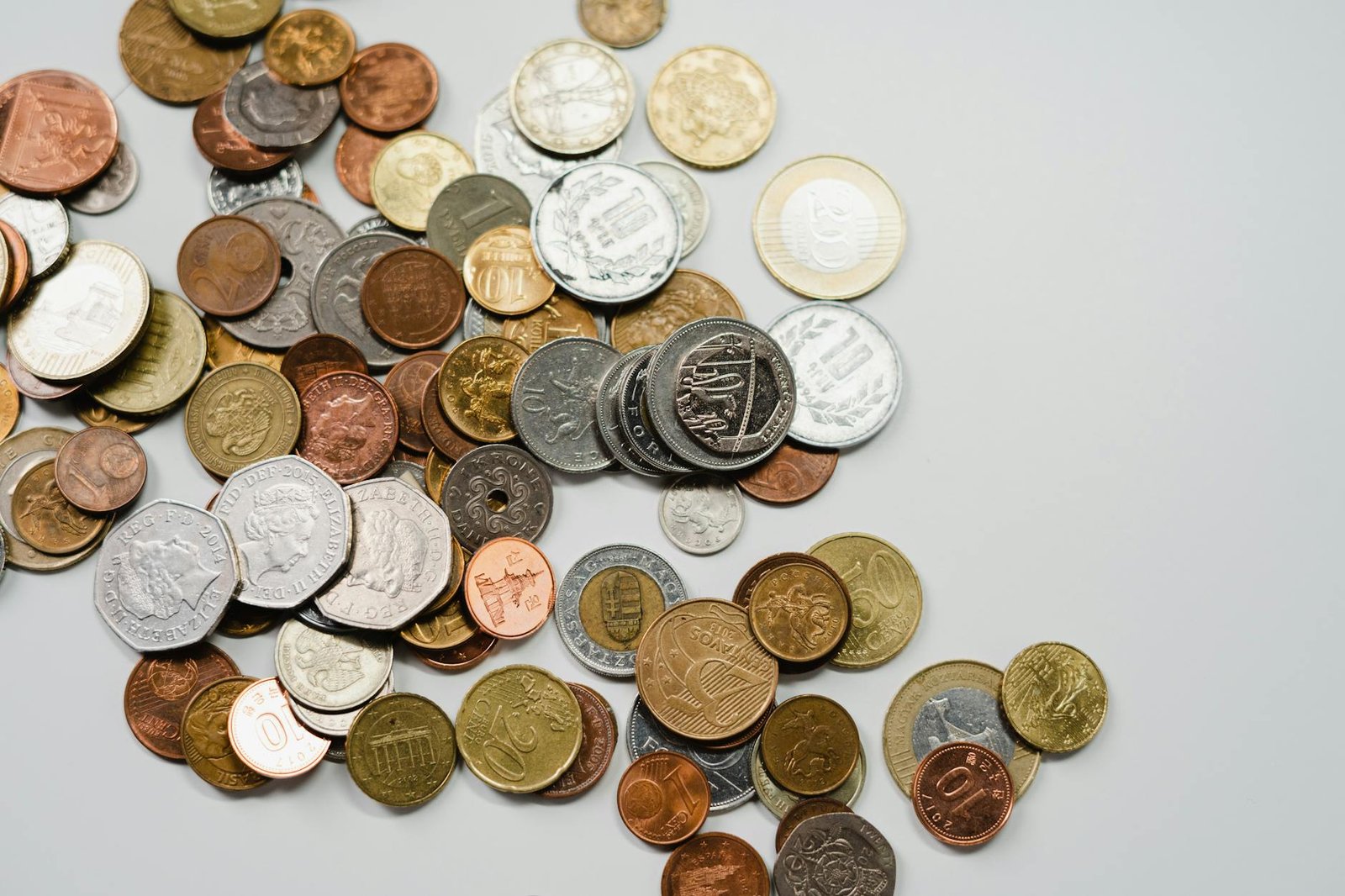 A collection of various international coins spread on a soft white background.