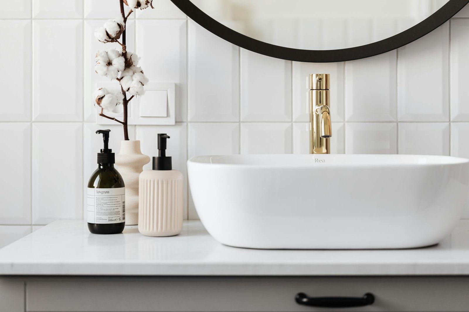 Stylish minimalist bathroom with a ceramic basin and modern gold faucet.