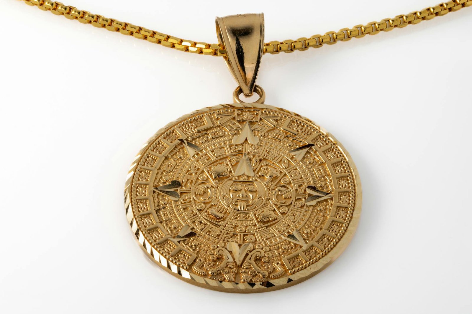 Close-up of a luxury gold pendant necklace with detailed Aztec calendar design, showcasing craftsmanship.